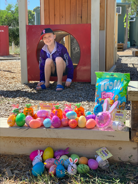 a child posing next to a pile of easter eggs