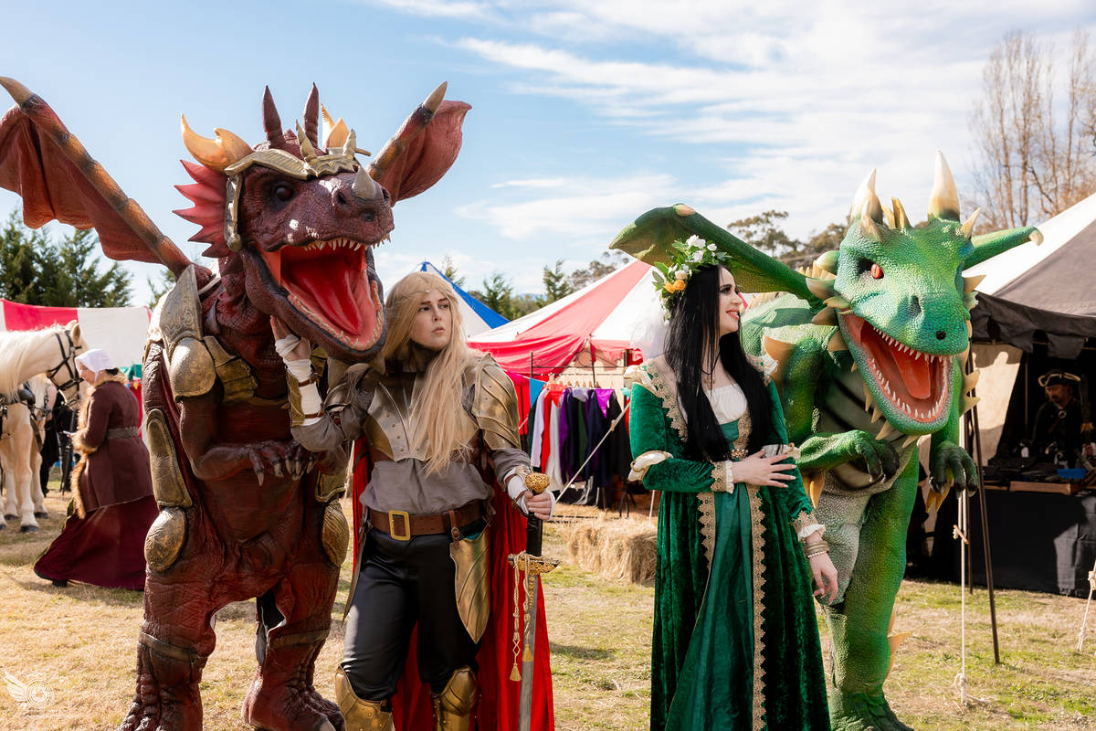 two people standing next to two fake dragons